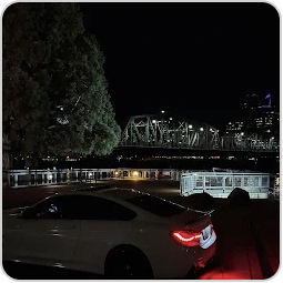 Nageeb’s BMW parked beside a lit bridge at night