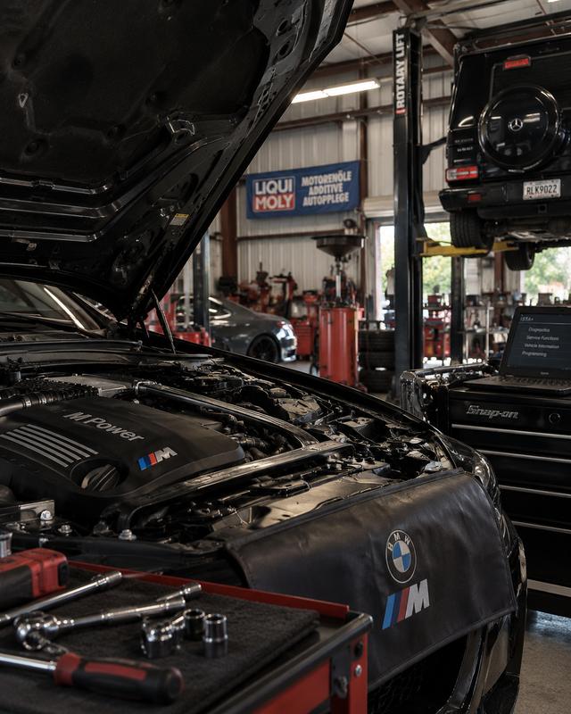Technician diagnosing a BMW M engine bay on a lift at German Performance